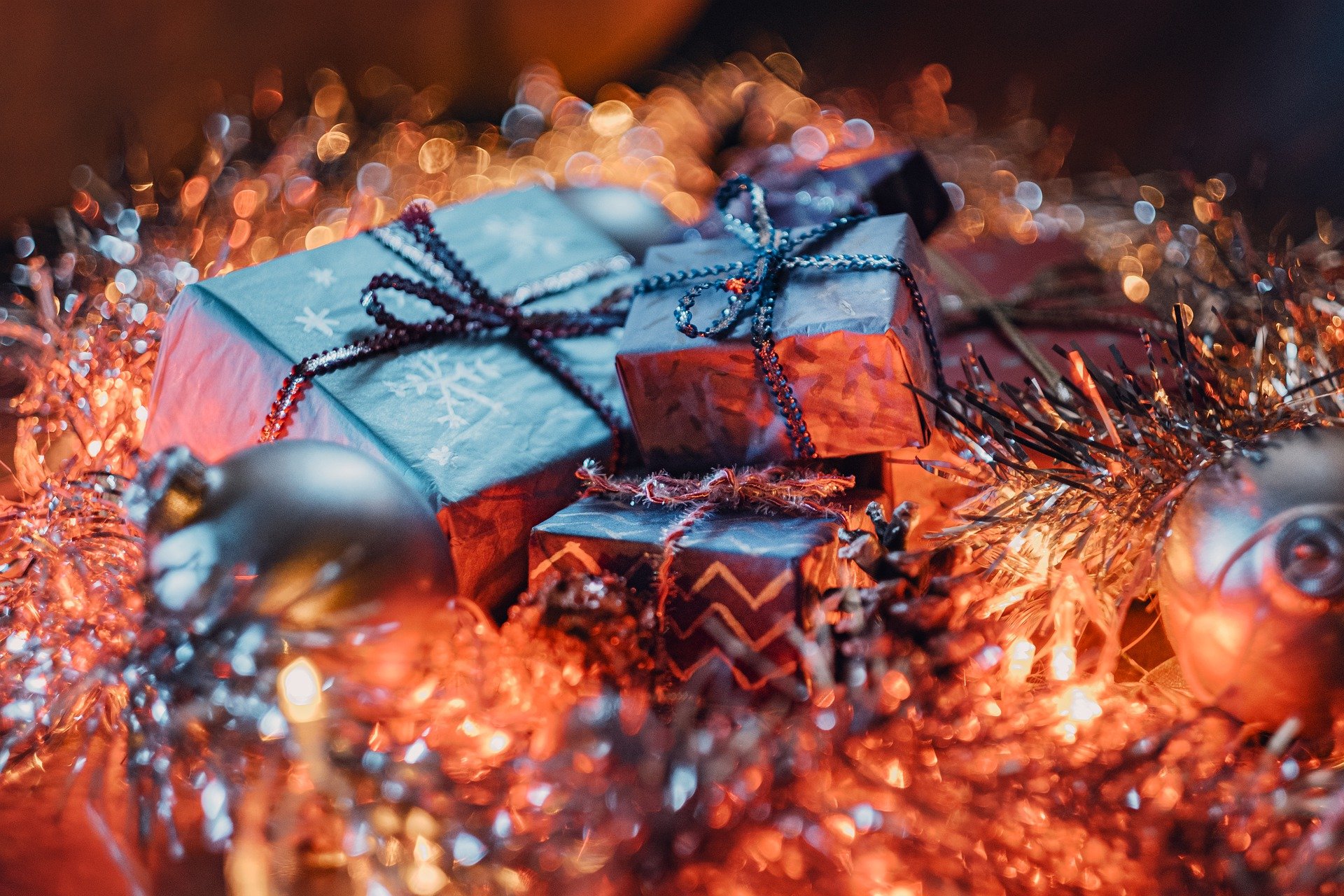 Unos regalos relucientes entre adornos navideños.